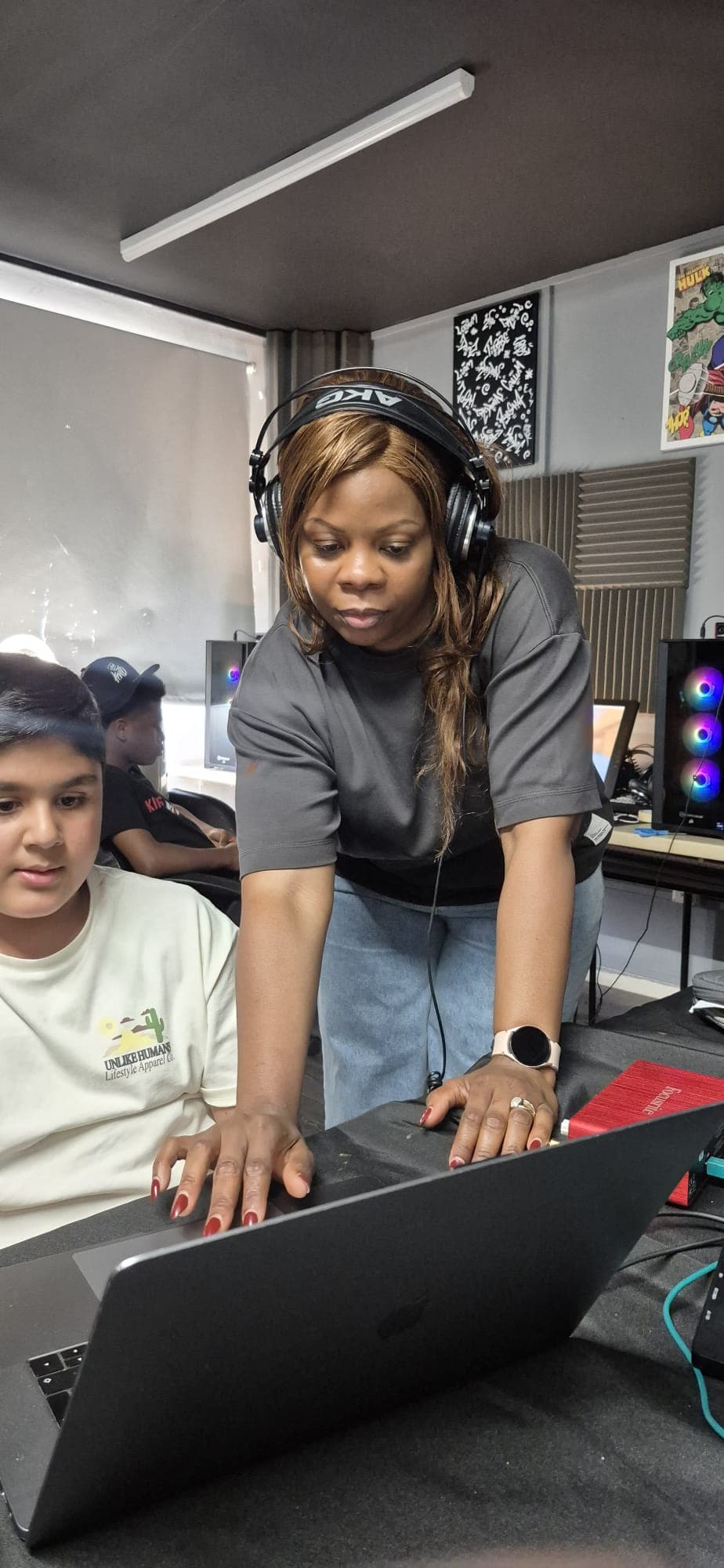 A trainer giving one-to-one support to a participant at a laptop in the recording studio