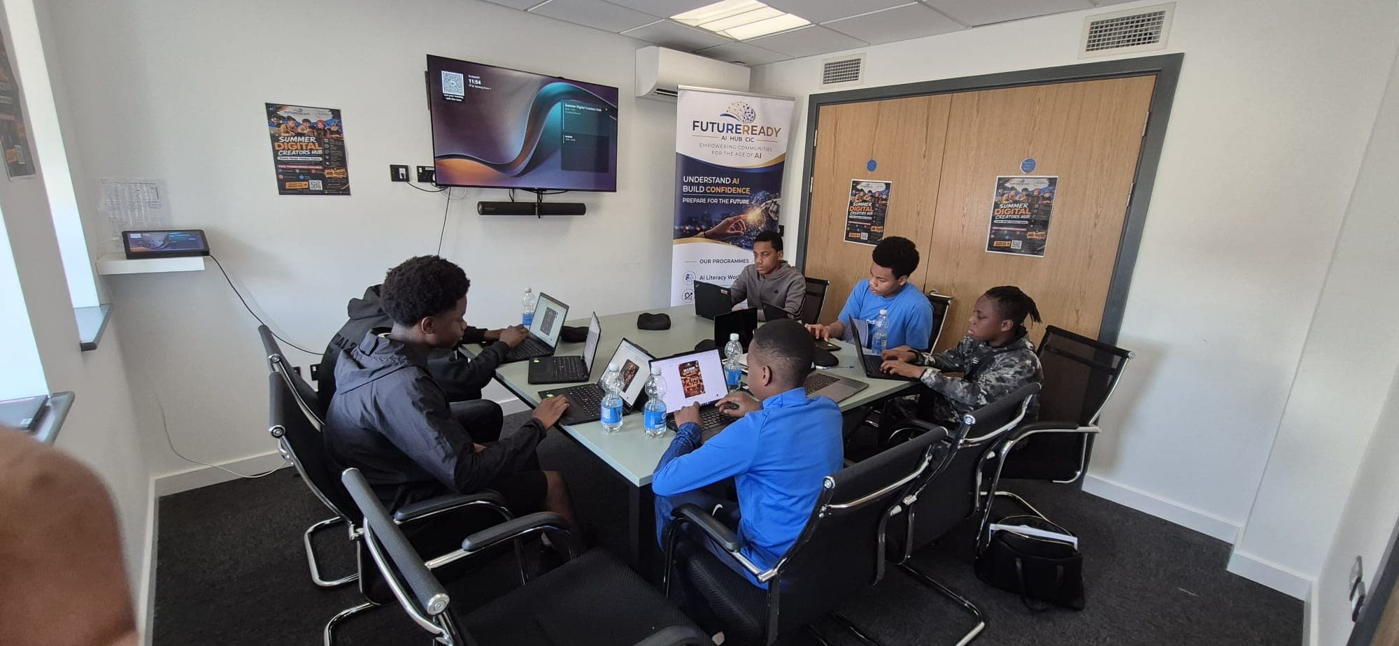 Participants working together on their projects around a table at the digital hub